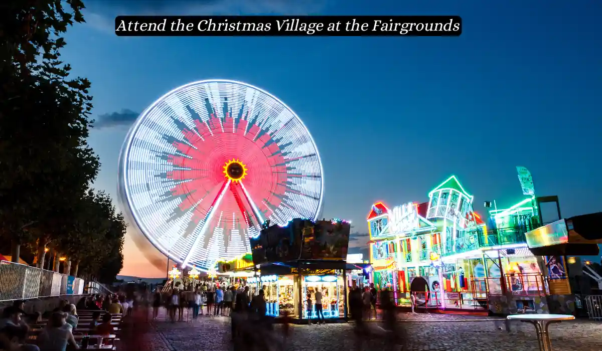 Top 15 Romantic Things to do in Nashville Tennessee for Couples 12 A bustling fairground with a giant ferris wheel glowing with red and white lights dominates the evening sky. Brightly lit carnival rides and booths form a festive Christmas Village atmosphere. A banner at the top reads, "Attend the Christmas Village at the Fairgrounds.