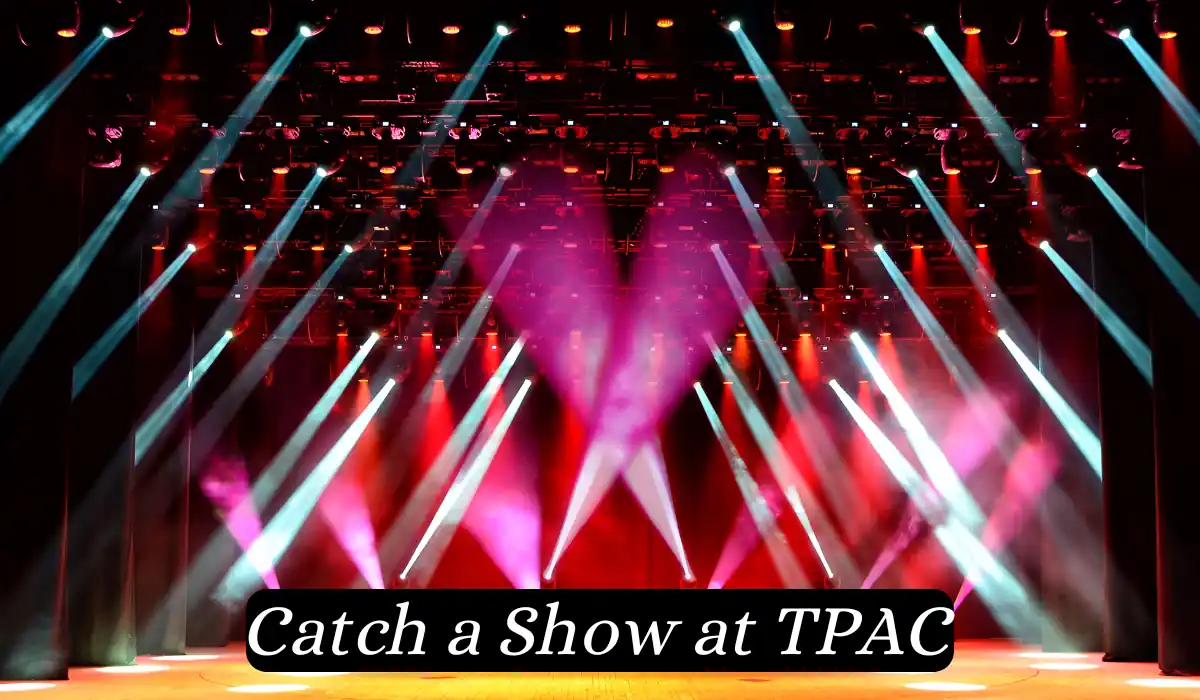 Top 15 Romantic Things to do in Nashville Tennessee for Couples 16 A vibrant stage with pink and white lights shining into the air, forming a heart shape. The background is dark with numerous spotlights creating a lively and dynamic atmosphere. Text at the bottom reads, "Catch a Show at TPAC.