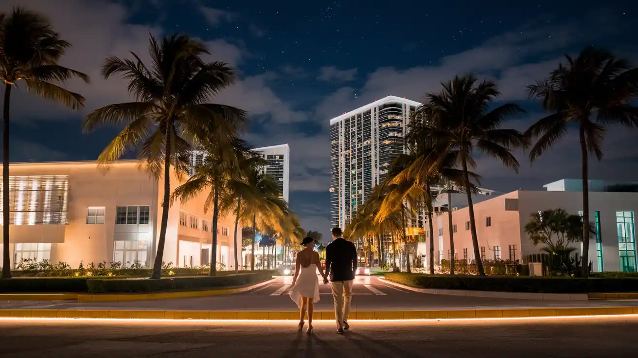 15 Best Things to do in Miami Florida for Couples at Night 22 A couple holding hands walks down a palm-lined street at night, with modern buildings on either side and a starry sky above. The street is illuminated by soft, warm lighting, creating a romantic atmosphere.