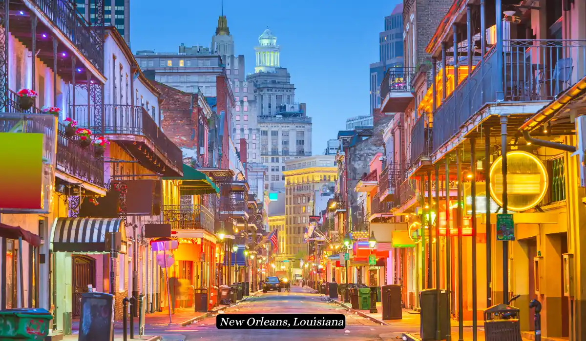 12 Best Places to Visit in November for Couples 2025 10 A vibrant street scene in New Orleans, Louisiana, showcasing colorful buildings adorned with neon lights and balconies. The street is lined with various establishments, and tall buildings are visible in the background during the early evening.