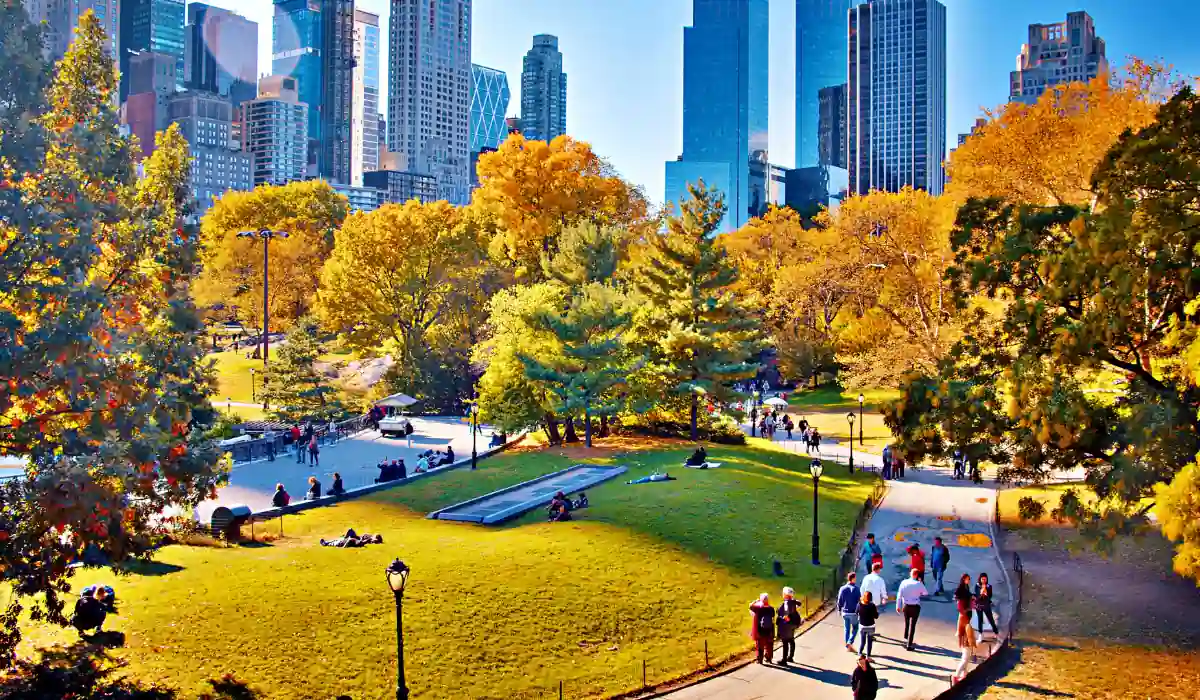 Top 15+ Free Things to do in Atlanta for Couples 2025 15 A Atlantic city park in autumn with people walking and relaxing on the grass. Surrounding trees display vibrant yellow and orange foliage. Tall skyscrapers tower in the background under a clear blue sky.