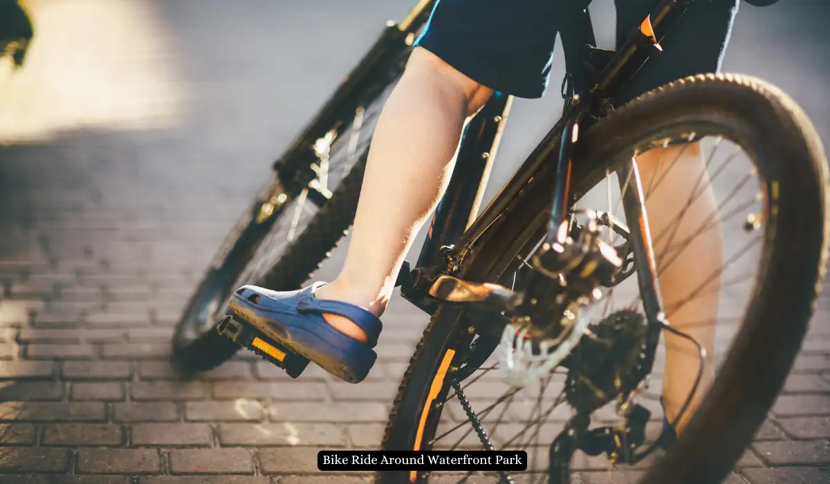 Top 15+ Romantic Things to do in Portland for Couples 17 A person wearing blue Crocs rides a bicycle on a sunlit brick path. The image focuses on the rider's legs and the bike, suggesting movement and a leisurely outdoor activity.
