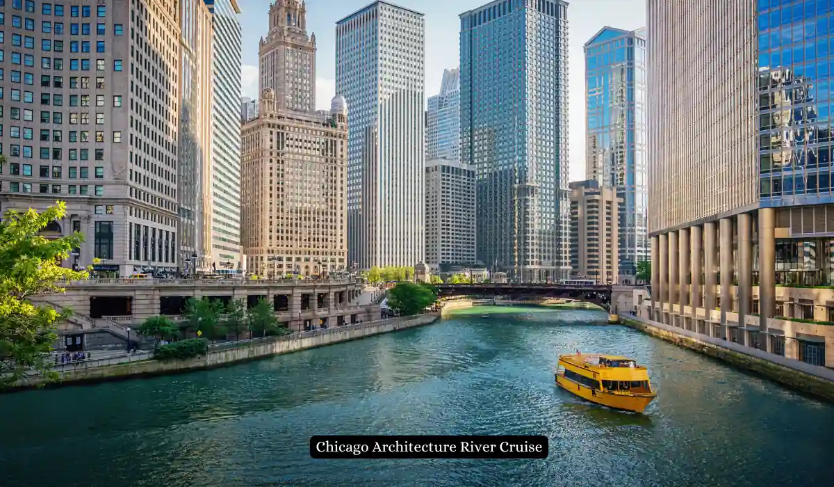 Top 15 Romantic Things to Do in Chicago for Couples 6 A yellow boat cruises on the Chicago River, flanked by towering skyscrapers that make up the city skyline on a sunny day. Lush greenery lines sections of the riverbank, adding a touch of nature to the urban landscape.