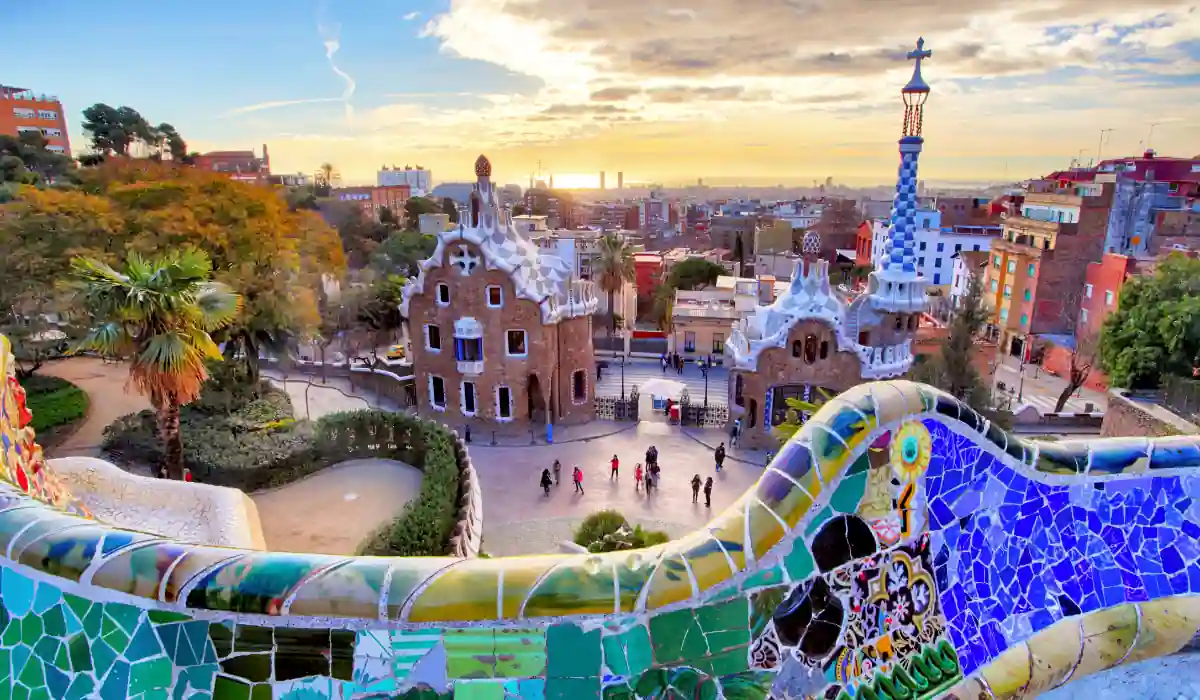 The 15 Best Things to Do in New Orleans for Couples 6 View of Park Güell in Barcelona at sunset, showcasing the colorful mosaic walls, whimsical architecture by Antoni Gaudí, and a panoramic view of the cityscape in the background. Visitors walk along the pathways amidst lush greenery.