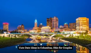 City skyline of Columbus, Ohio, at dusk with illuminated buildings and a bridge reflecting on the river. Text overlay says, "Cute Date Ideas in Columbus, Ohio for Couples.