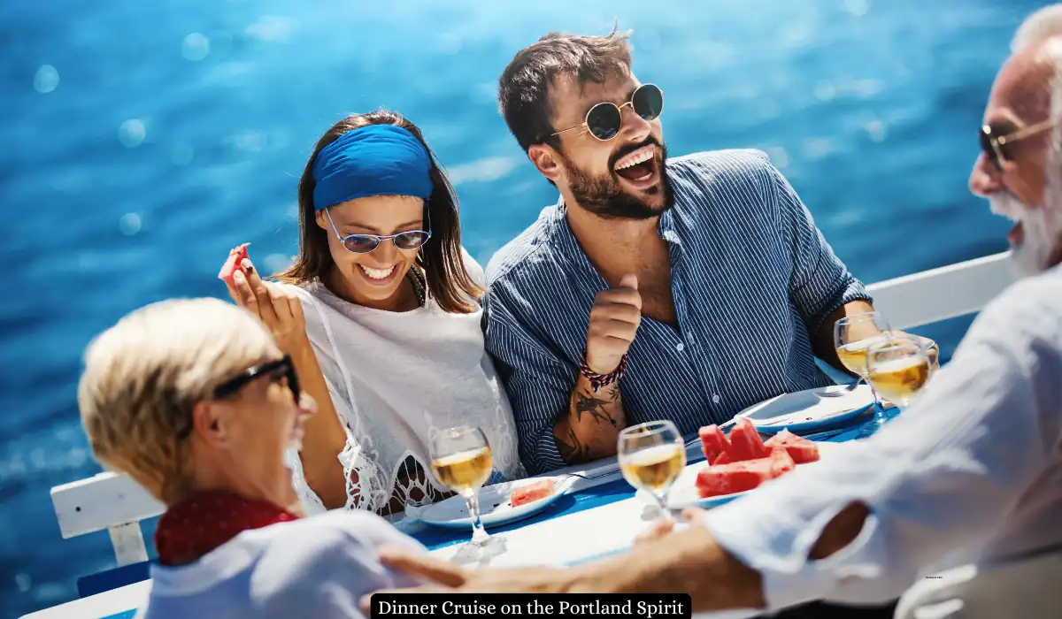 Top 15+ Romantic Things to do in Portland for Couples 6 Four people are laughing and enjoying a sunny meal on a boat. They are gathered around a table with glasses of wine and plates of watermelon. The ocean is visible in the background, and they appear relaxed and happy.