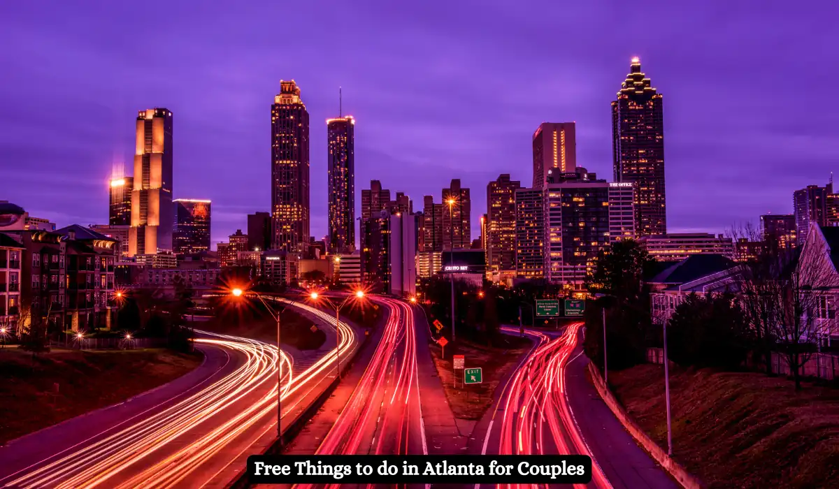 A vibrant, nighttime view of Atlantas skyline with streaking car lights on the highway below. The buildings are illuminated against a purple sky. Text at the bottom reads, Free Things to do in Atlanta for Couples.
