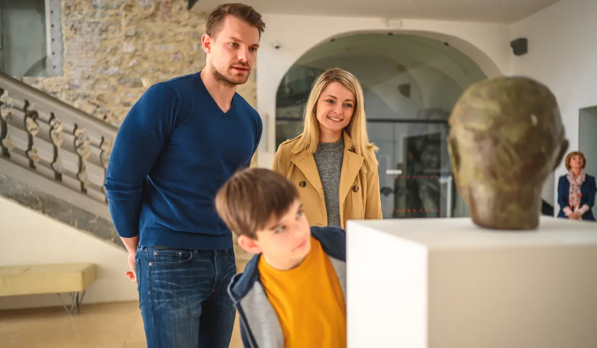 40 amazing Cute Date Ideas in Columbus, Ohio for Couples in 2025 15 A family of three, consisting of a man, a woman, and a child, is observing a sculpture on display in a museum. The child leans in closely to look at the artwork. The room has bright lighting and a modern design.