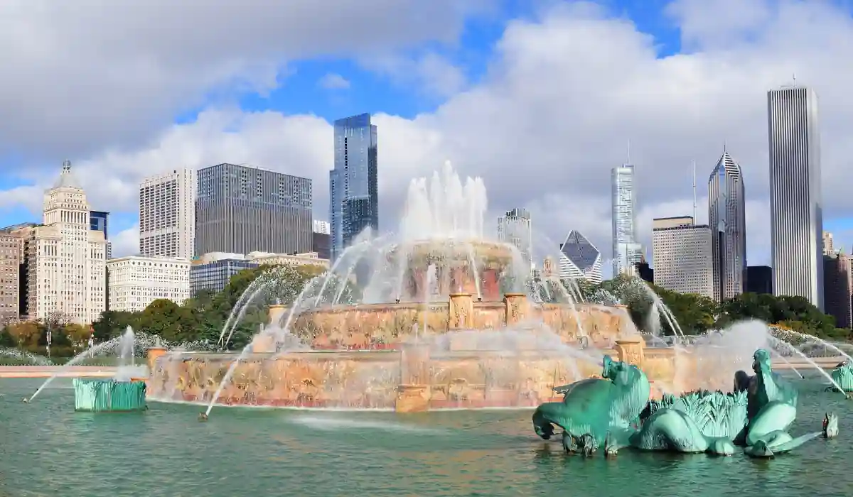 Top 15+ Free Things to do in Atlanta for Couples 2025 11 A large, ornate fountain with water jets is set against a city skyline featuring tall skyscrapers. The sky is blue with scattered clouds, and greenery surrounds the fountains base.