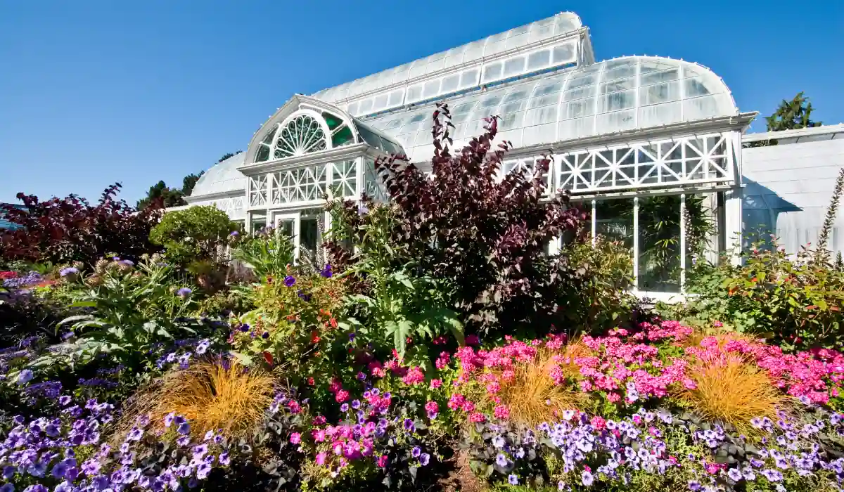 40 amazing Cute Date Ideas in Columbus, Ohio for Couples in 2025 41 A beautiful greenhouse with a glass dome roof surrounded by a vibrant garden full of colorful flowers and lush greenery under a clear blue sky.