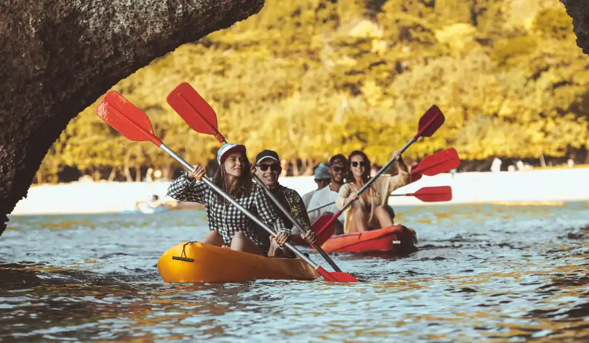 20 Most Romantic Things to do in California for Couples 12 A group of people kayaking on a serene body of water, with lush, sunlit trees in the background. They are paddling in colorful kayaks, appearing to enjoy a leisurely outdoor adventure.