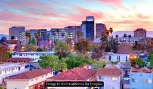 A vibrant cityscape of California at sunset, featuring tall buildings and palm trees with a foreground of residential houses. The sky is painted in hues of pink and orange. A banner reads, Things to do in California for Couples.