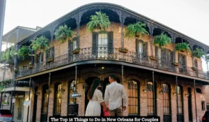A couple stands in front of a historic New Orleans building with ornate ironwork balconies adorned with hanging plants. The building is two stories tall with large windows. Text at the bottom reads: The Top 15 Things to Do in New Orleans for Couples.