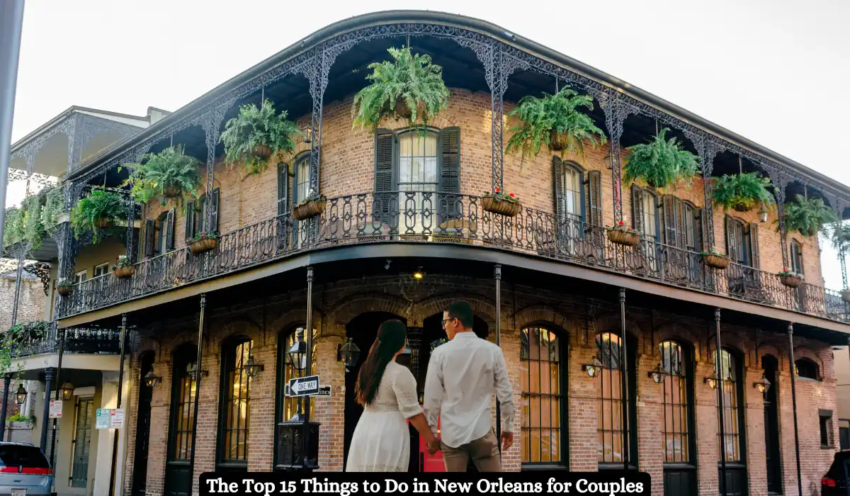 A couple stands in front of a historic New Orleans building with ornate ironwork balconies adorned with hanging plants. The building is two stories tall with large windows. Text at the bottom reads: The Top 15 Things to Do in New Orleans for Couples.