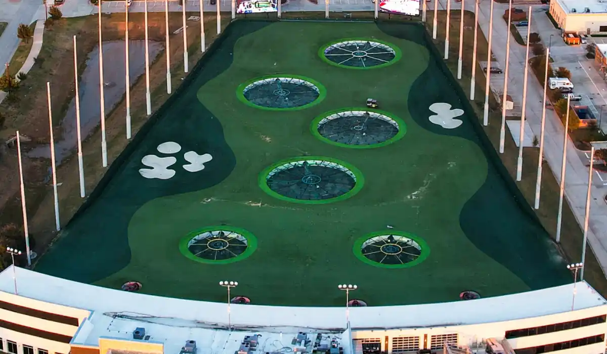 40 amazing Cute Date Ideas in Columbus, Ohio for Couples in 2025 12 Aerial view of a golf driving range with large target circles on a turf field. Six white sand traps are visible on both sides. Surrounding the range are buildings and parking areas.
