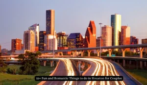 A view of Houstons skyline during sunset with light trails from cars on a highway. Tall buildings reflect the warm colors of the setting sun, creating a dynamic urban landscape.