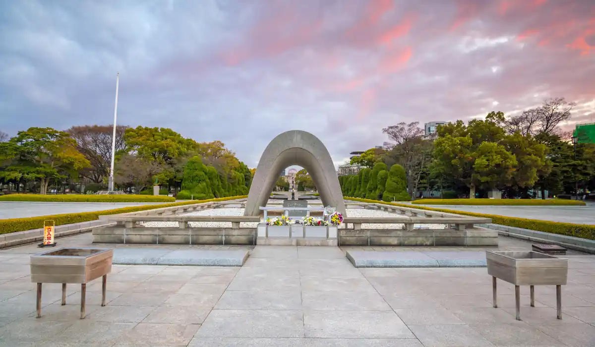 15+ Fun and Romantic Things To Do In Houston for Couples 16 A peaceful scene of the Hiroshima Peace Memorial Park at sunset, featuring the Memorial Cenotaph surrounded by green trees. The sky is painted with soft shades of pink and purple.