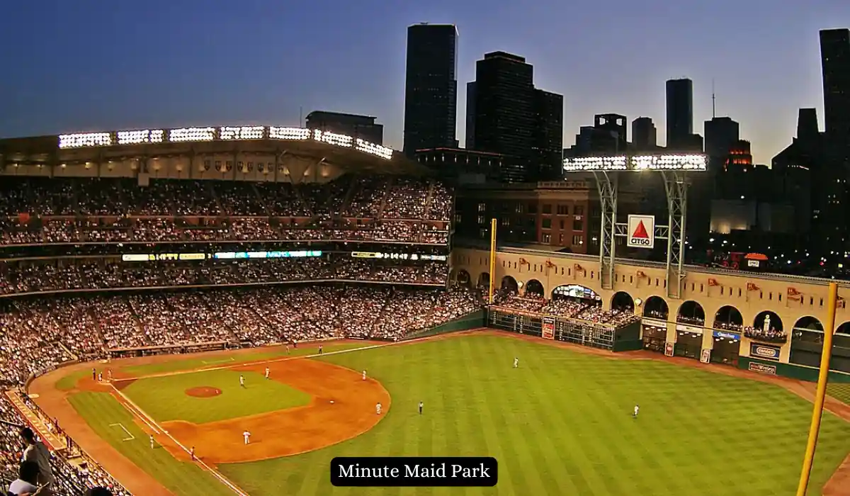 15+ Fun and Romantic Things To Do In Houston for Couples 7 A baseball game at Minute Maid Park during sunset. The stadium is filled with spectators, and players are on the field. The city skyline is visible in the background, and the outfield wall displays advertisements.