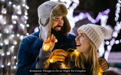 Top 15 Romantic Things to Do at Night for Couples A couple in warm clothing is playfully wrapped in string lights, smiling at each other outdoors at night. The background features softly glowing white lights, creating a festive and romantic atmosphere. "Romantic Things to Do at Night for Couples"