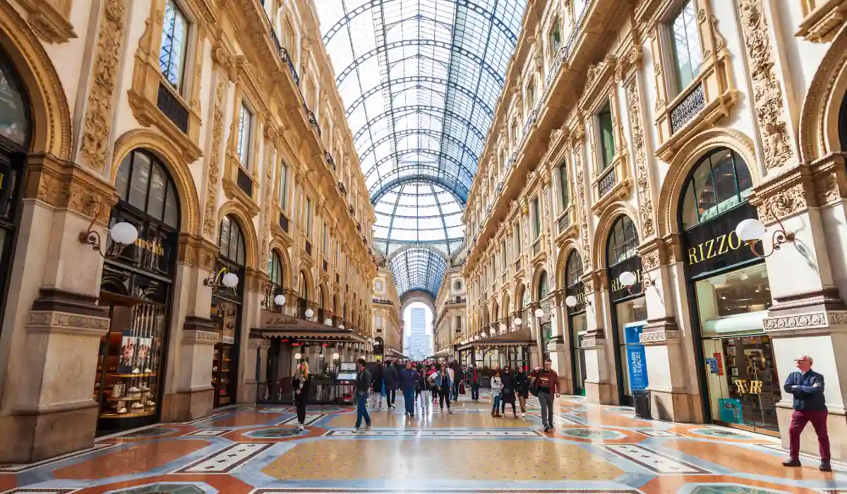 15+ Fun and Romantic Things To Do In Houston for Couples 5 A bustling shopping arcade with a glass-vaulted roof, ornate architecture, and an intricate tiled floor. People are walking and shopping, surrounded by elegant storefronts and soft lighting.