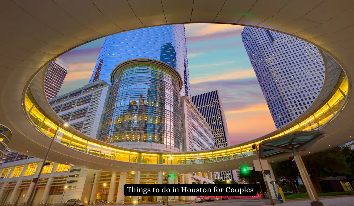 15+ Fun and Romantic Things To Do In Houston for Couples 2 A view of downtown Houston skyscrapers seen through a circular architectural structure at sunset. The sky is vibrant with pink, orange, and blue hues. A caption reads, Things to do in Houston for Couples.