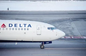Exclusive Delta Flight Dog Diversion MSP Shocks Travelers (2025) A Delta Air Lines airplane taxiing on a runway, photographed from the side, with snow visible in the background.
